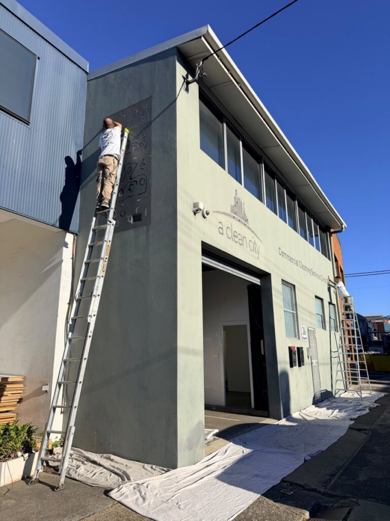 Commercial building exterior before repainting, with old signage being removed by AKD Painting, Sydney