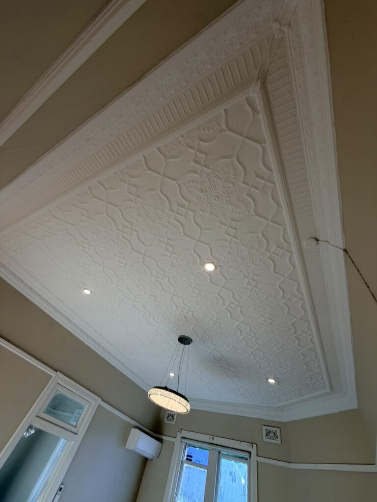 Restored ornate pressed metal ceiling painted crisp white by AKD Painting in an Inner West home, after