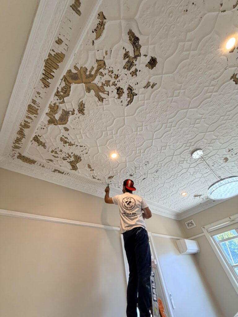 Ornate pressed metal ceiling being stripped and prepped by an AKD Painting painter in an Inner West home, before restoration