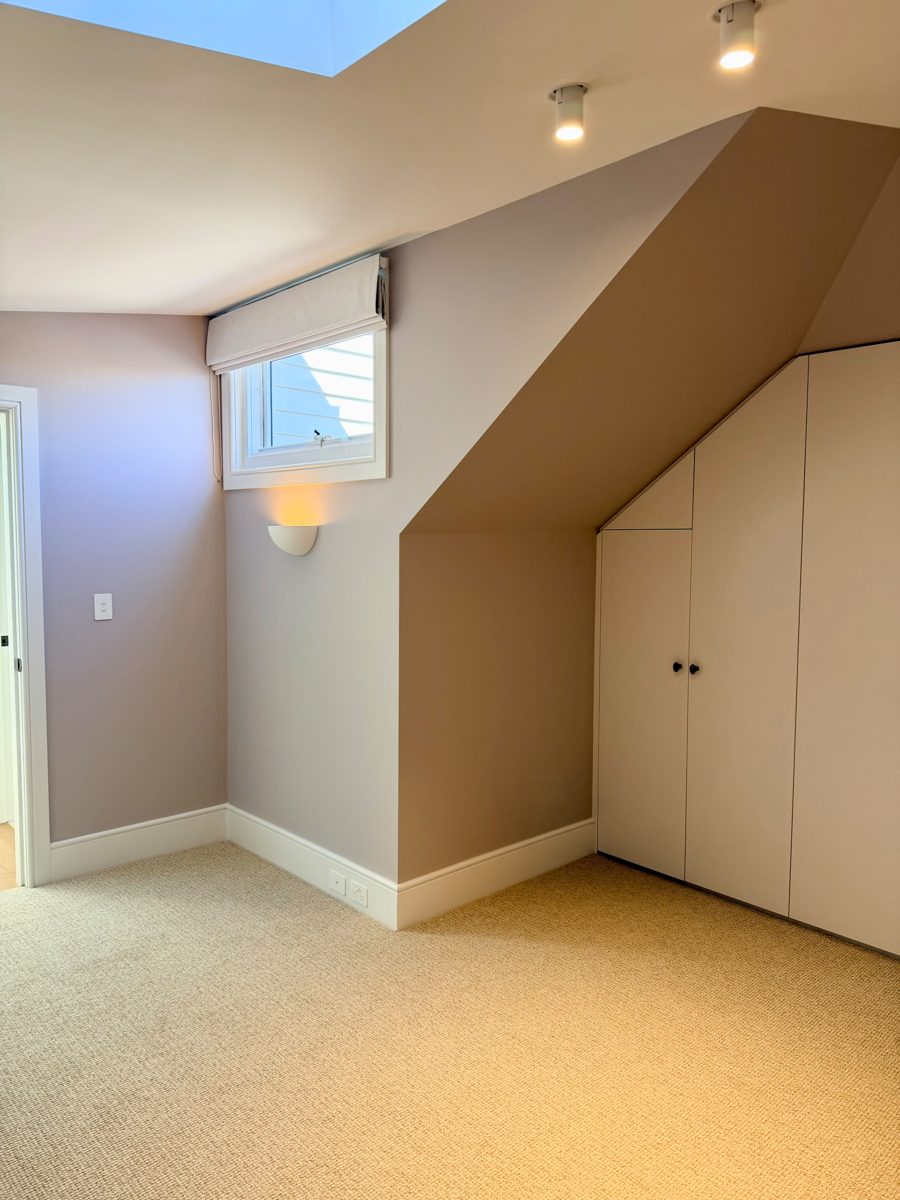 Finished attic room in an Annandale home with built-in joinery under the roofline painted to match the walls, new carpet
