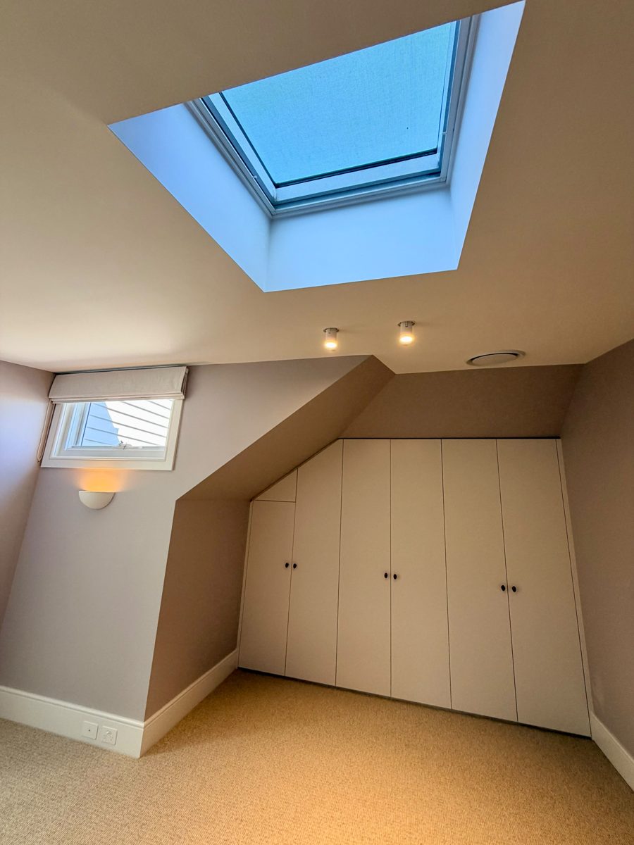 Attic room with skylight and built-in joinery painted to match the walls in Annandale