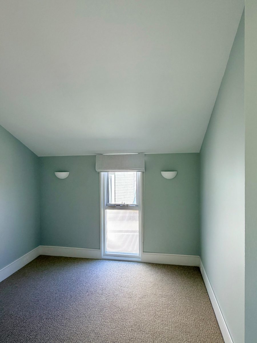 Bedroom painted in a soft sage green with white trims in an Annandale home