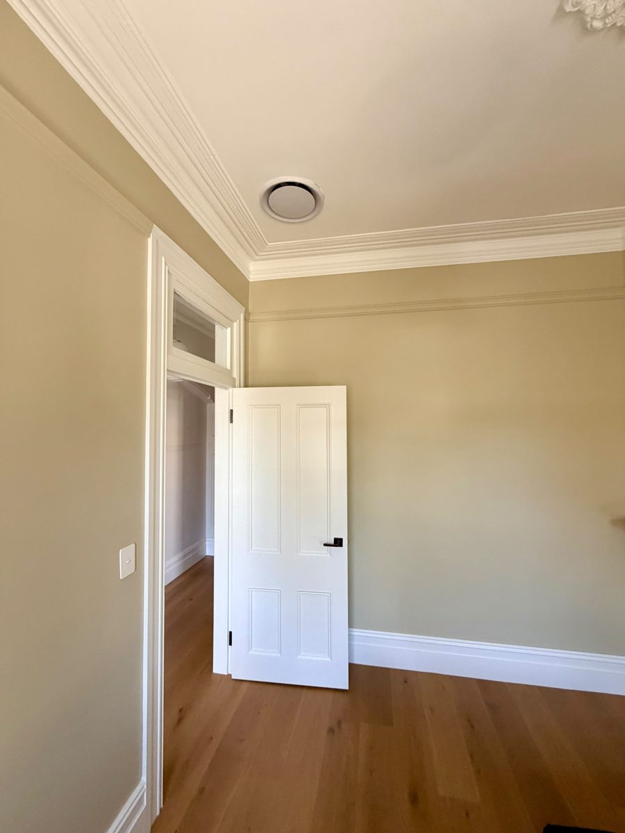 Repainted Federation-era room in Annandale with deep cornice, picture rail and white panel door
