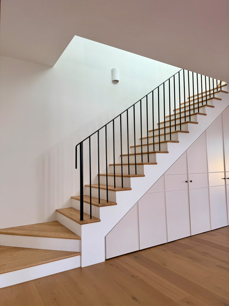 New timber staircase with black balustrade and painted under-stair joinery in an Annandale home