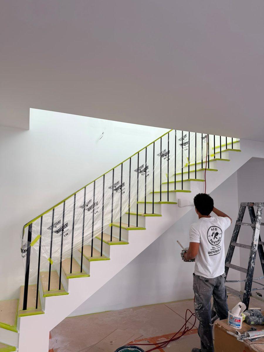 AKD painter cutting in the stair wall in an Annandale home with the treads and balustrade masked