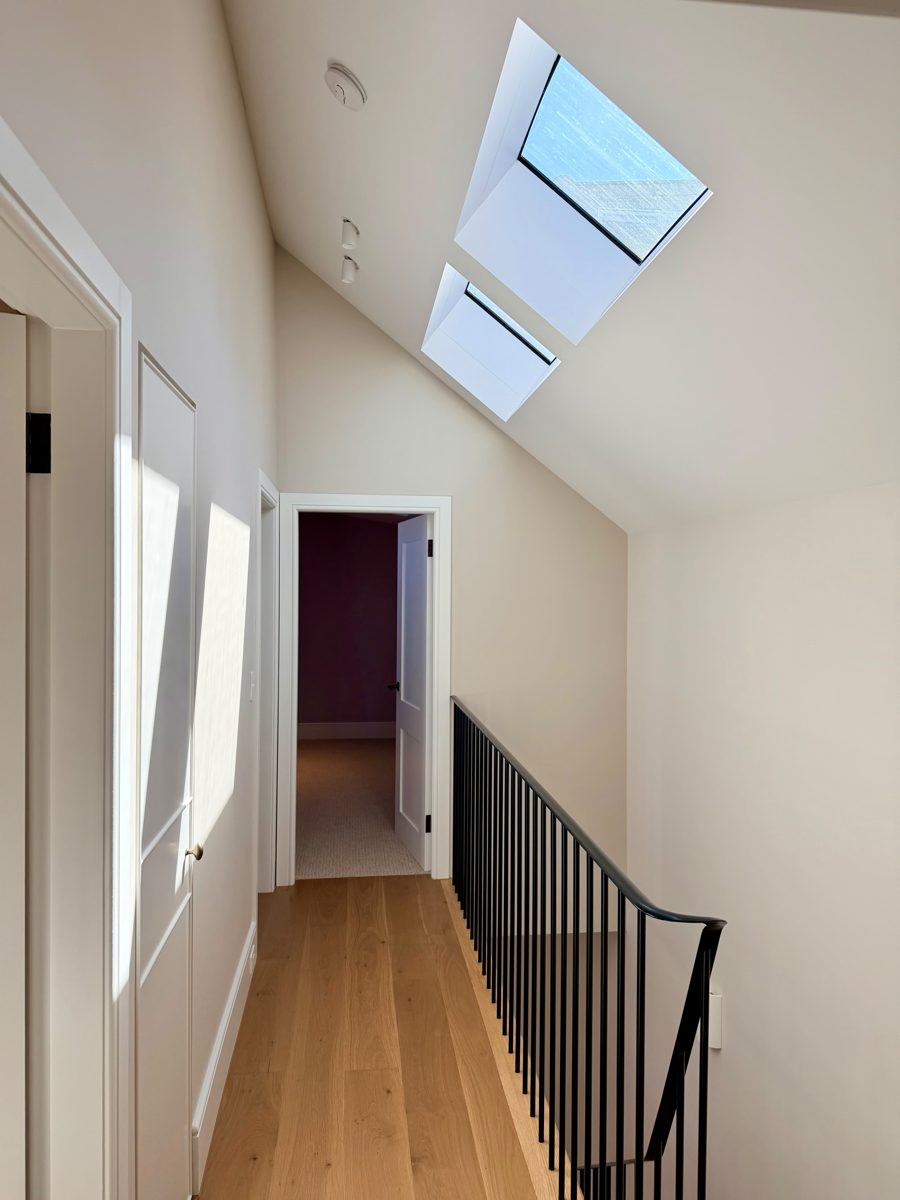 Upstairs hallway with two skylights and freshly painted raked ceiling in an Annandale home