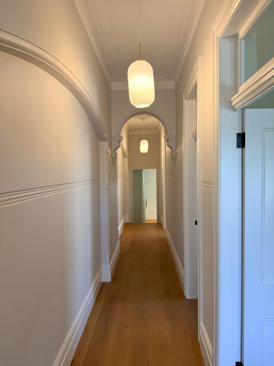 Repainted Victorian hallway with arched openings and pendant lights in an Annandale home