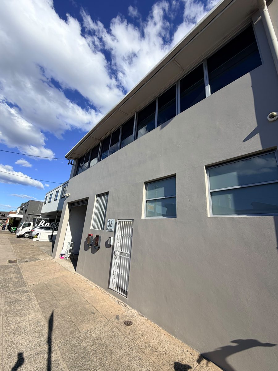 Two-storey rendered commercial building in Sydney after exterior repaint in mid grey