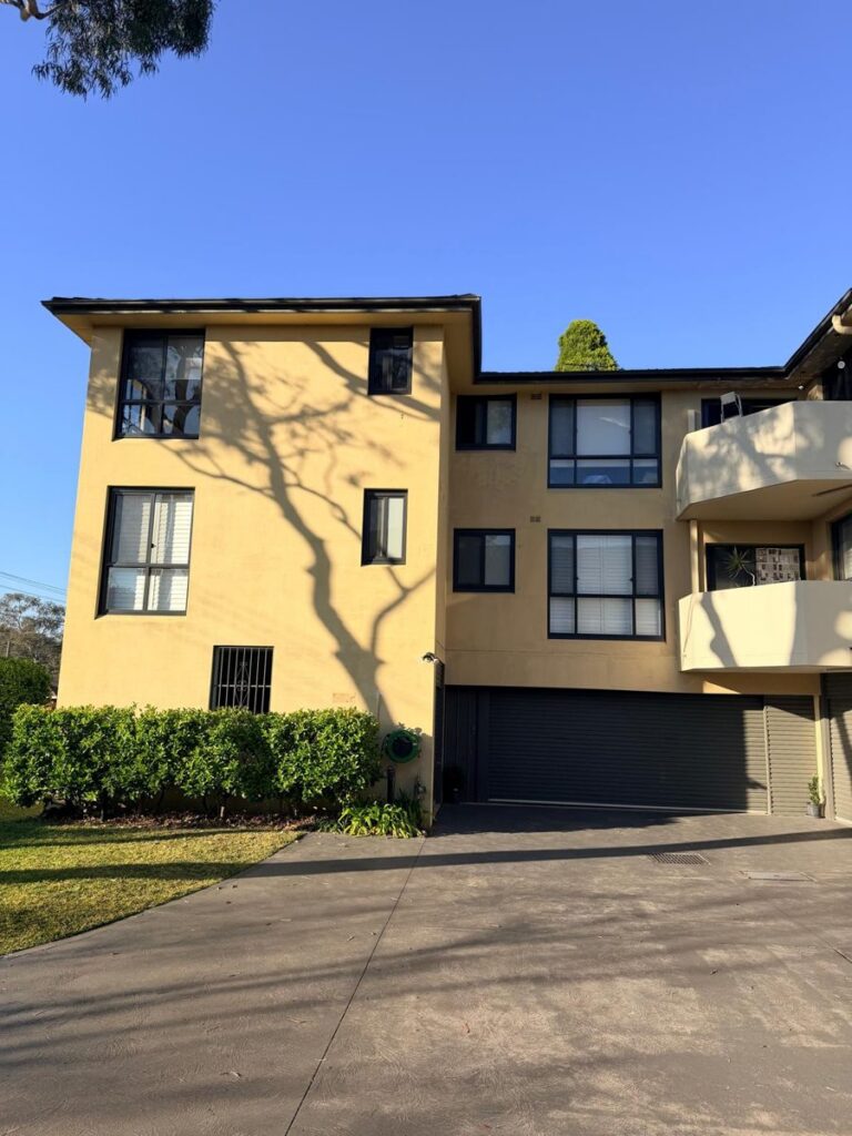 Three-storey strata walk-up in Canada Bay before repainting, ochre render and dark grey balconies
