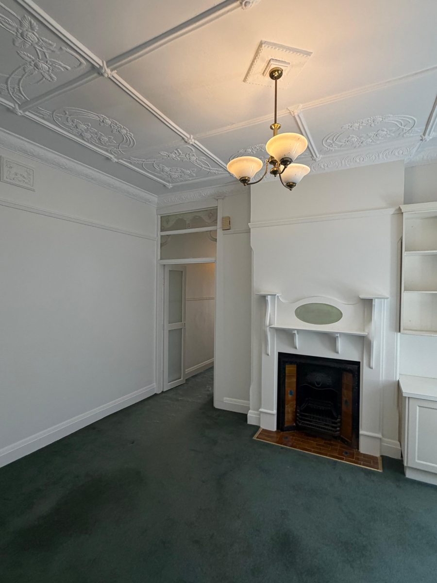 The same Five Dock front room after painting, white walls, fireplace and built-in shelves