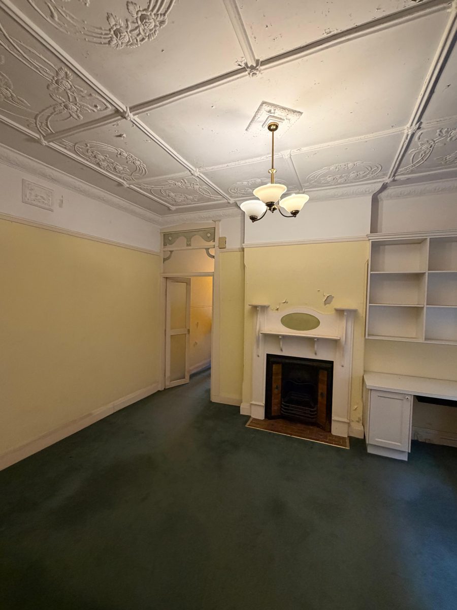 Front room of a Five Dock Federation home before painting, yellow walls, fireplace and pressed metal ceiling