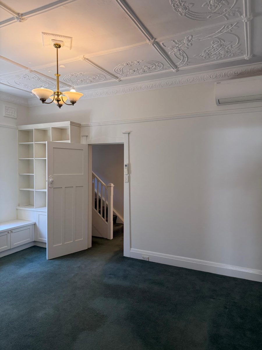Finished front room in a Five Dock Federation home with built-in shelves and the door to the stair