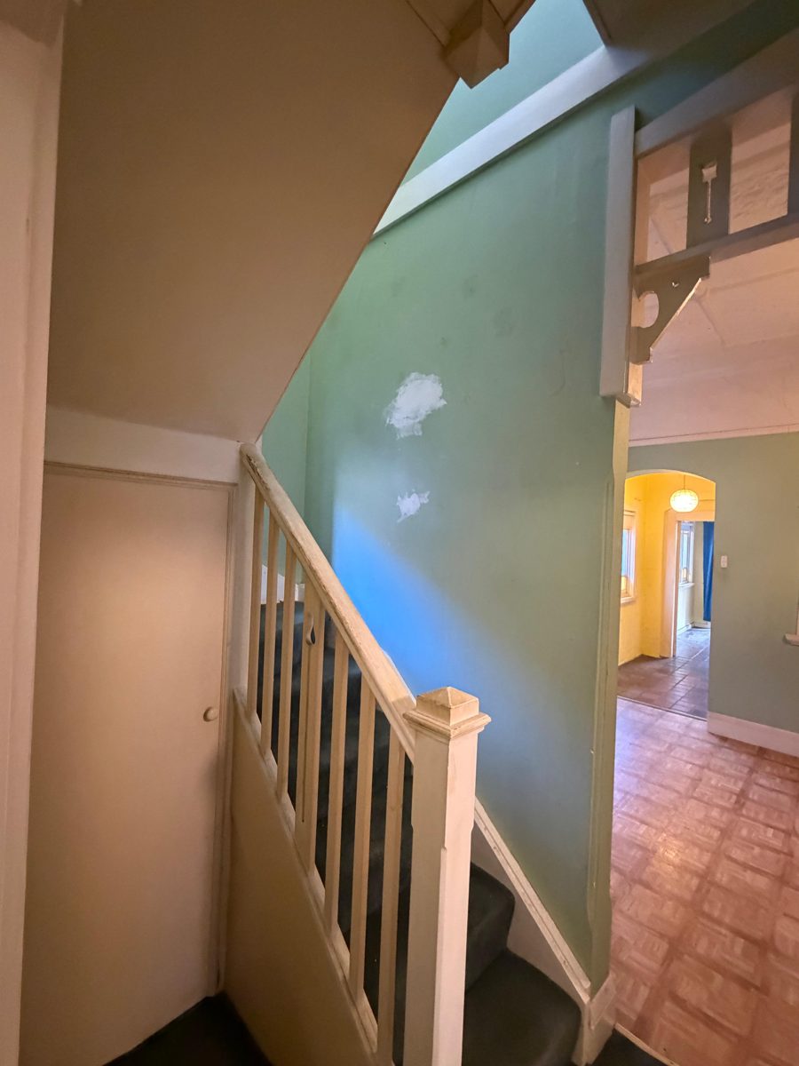 Stair hall in a Five Dock Federation home before painting, green walls with patch marks