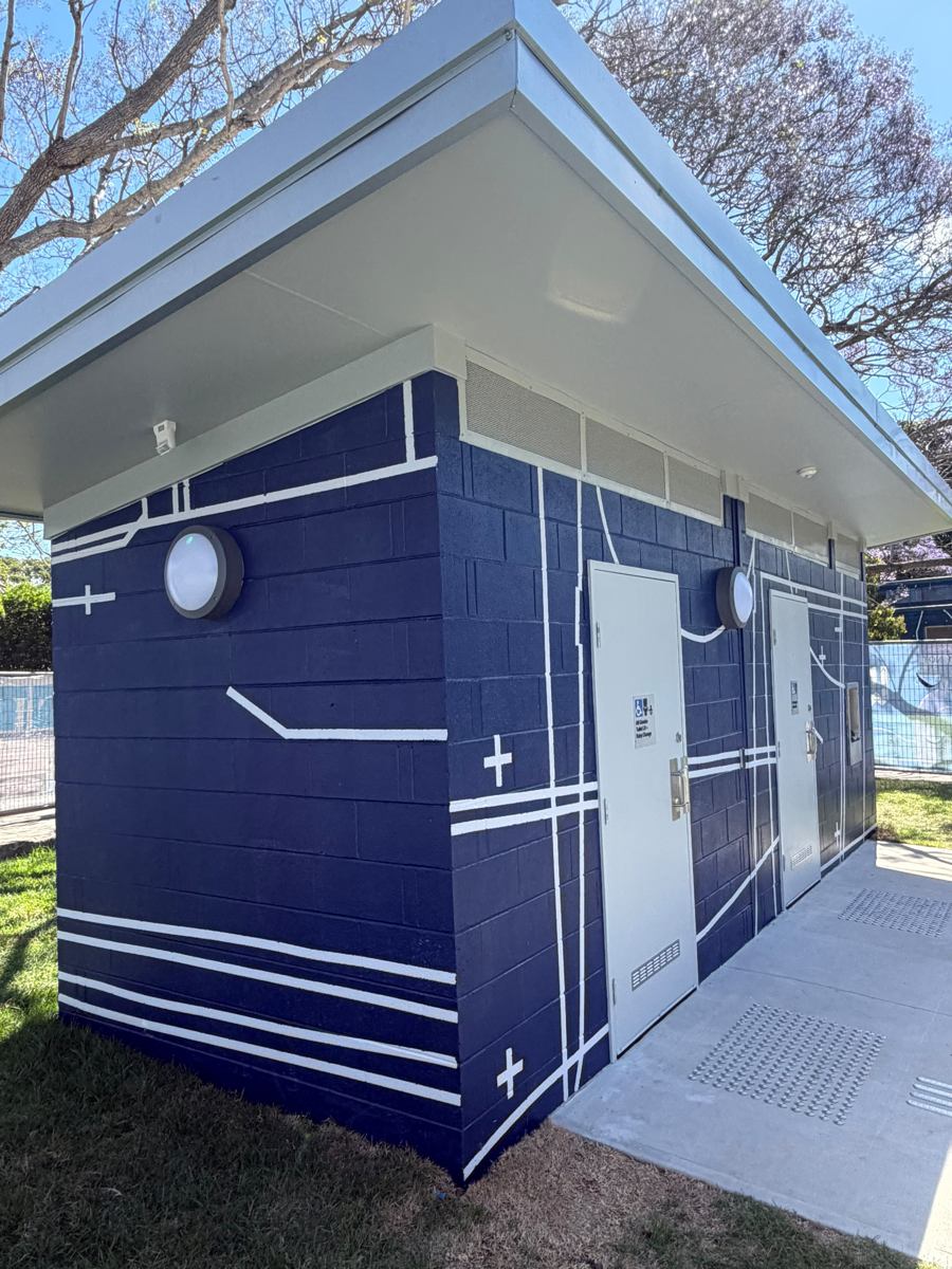 Door side of the finished Marrickville park amenities block, navy blockwork with white lines and plus marks