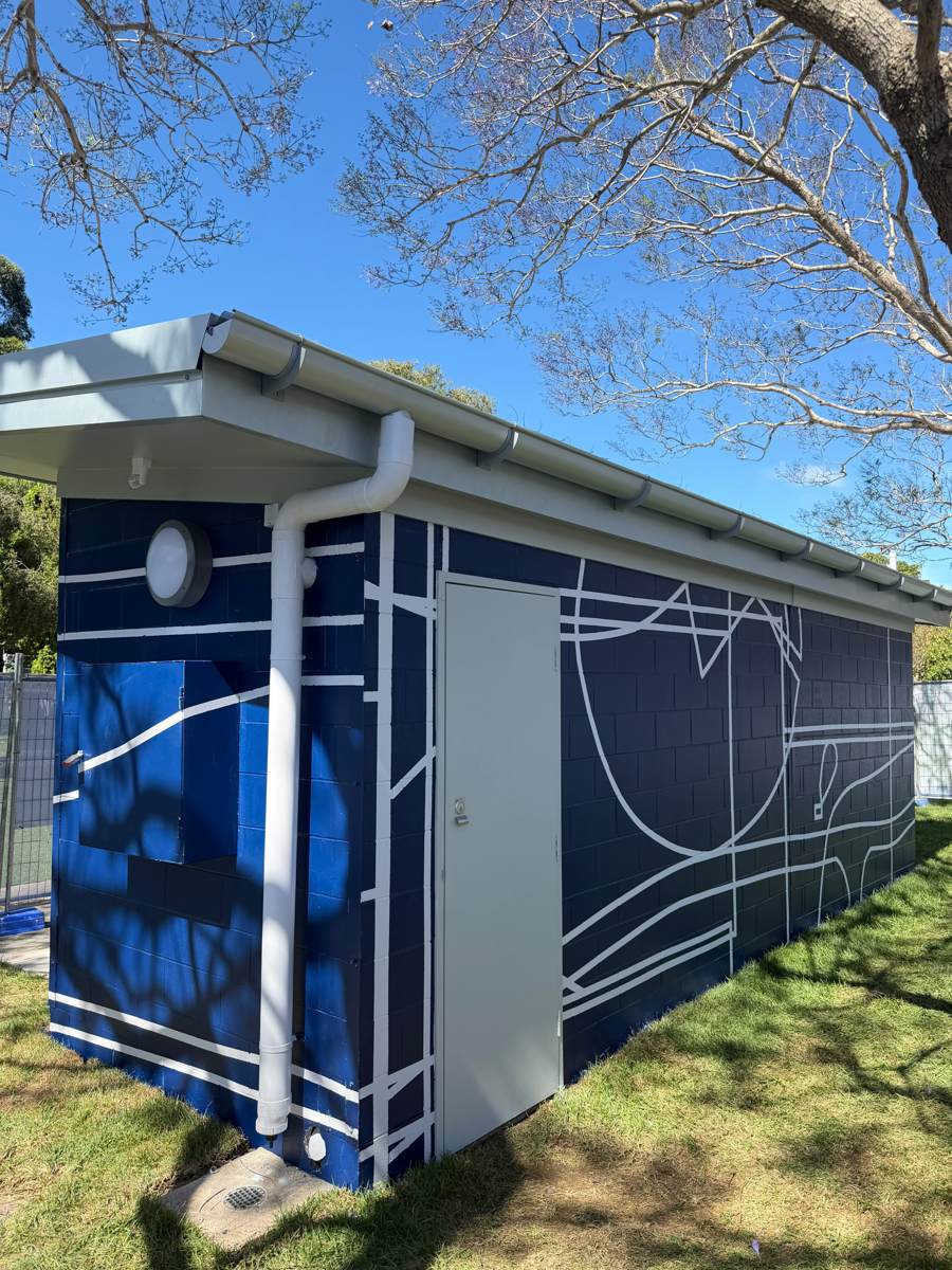 The same downpipe corner of the Marrickville amenities block finished in navy with white lines
