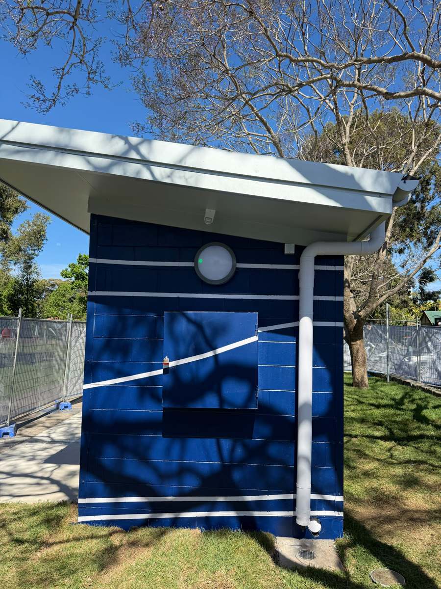 Rear wall of the finished Marrickville amenities block in navy with white lines around the downpipe